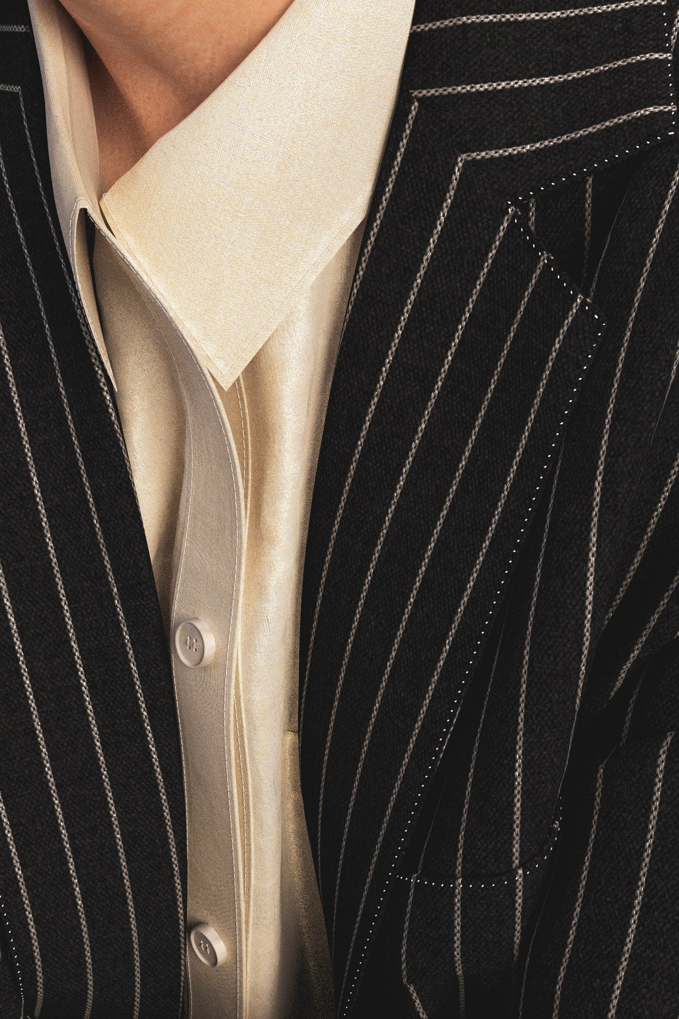 Digital suit jacket detail image of lapel. Jacket in black wool fabric with white pinstripe and button down shirt underneath is cream coloured.